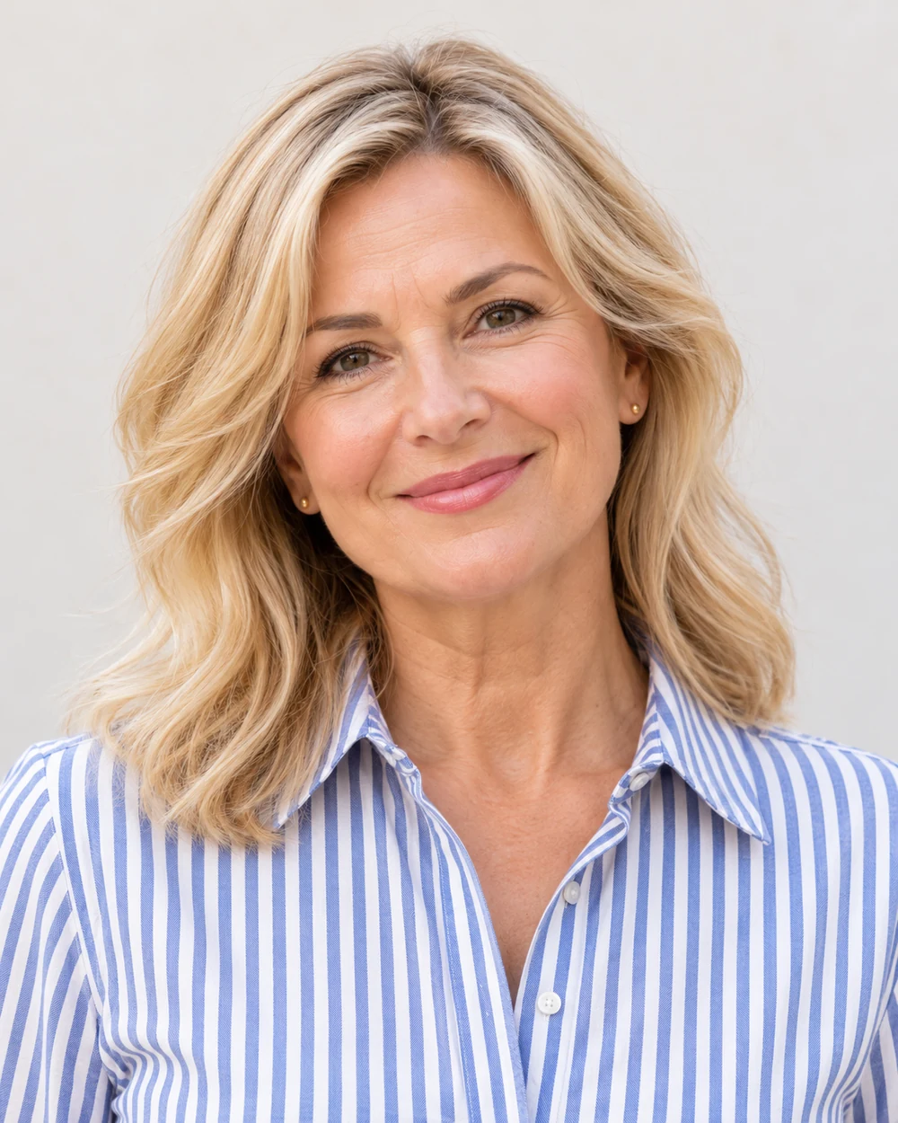 A fictional mature woman with fair light skin and blonde waves wearing a narrow brown lash line, warm rose cheeks and pink satin lips with a blue striped collar.