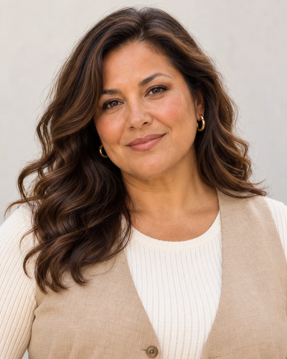 A fictional woman with warm golden-tan skin, brown waves and full facial proportions wearing soft cocoa outer lids, peach-brown cheeks and nude-brick lips with sand and ivory.