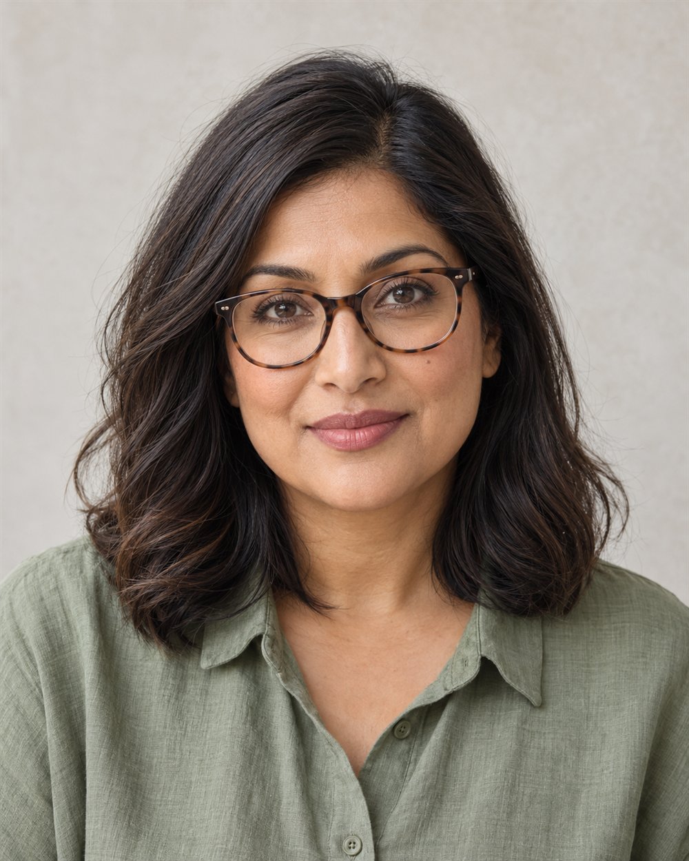 A woman wearing tortoiseshell glasses with a narrow brown upper-lash line and muted rose lips.