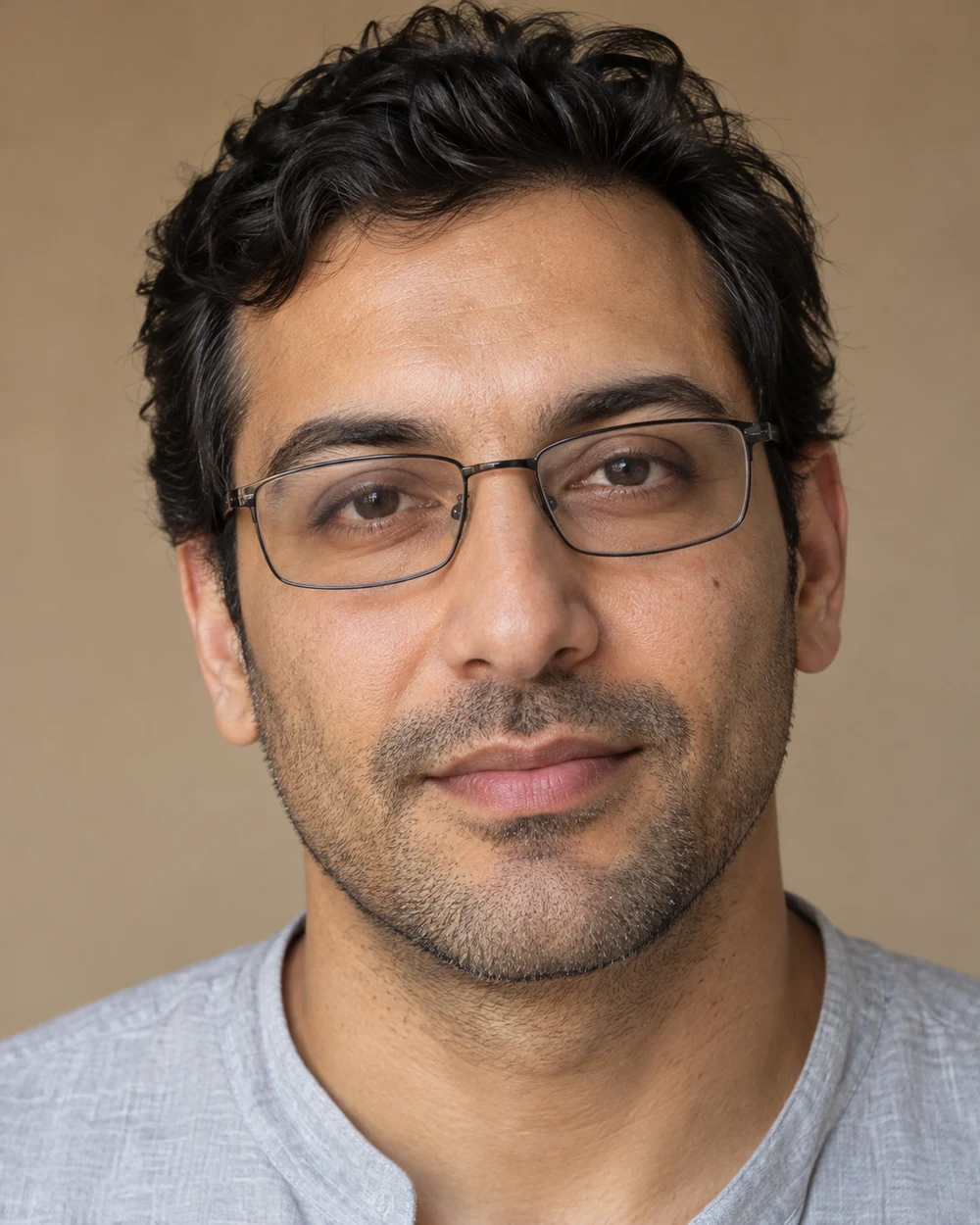 A fictional adult with medium olive skin wearing understated rectangular glasses, a contained grey-brown lid wash and a quiet natural lip.