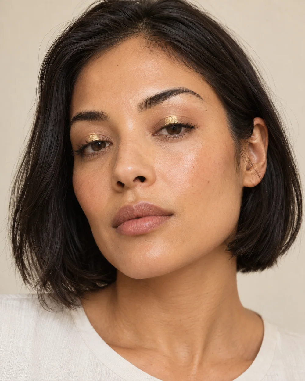 An adult with tan golden skin, natural skin texture and a small gold lid centre with quiet edges.