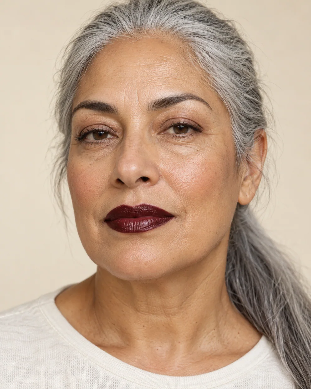 An adult with medium olive skin, natural skin texture and a blackened cherry mouth with a satin sheen.