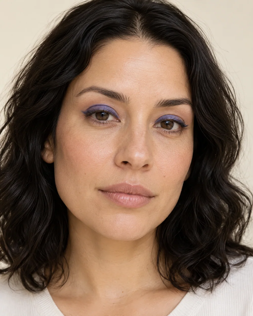 An adult with light-medium neutral skin, natural skin texture and a blue-violet upper-lid accent.