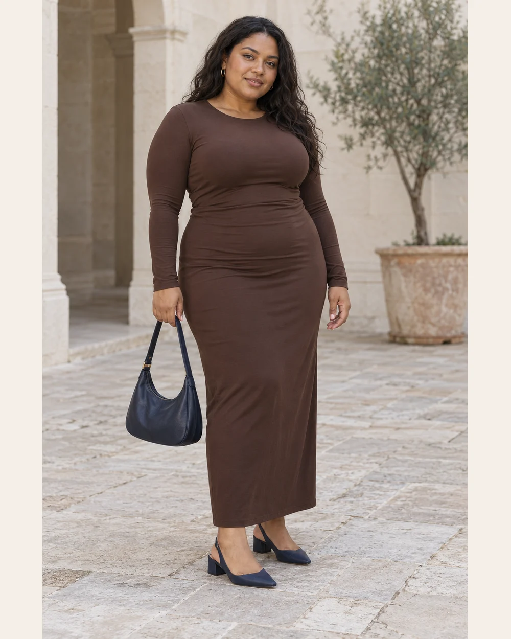 A fictional woman in chocolate column dress, navy block-heel slingbacks and navy bag.