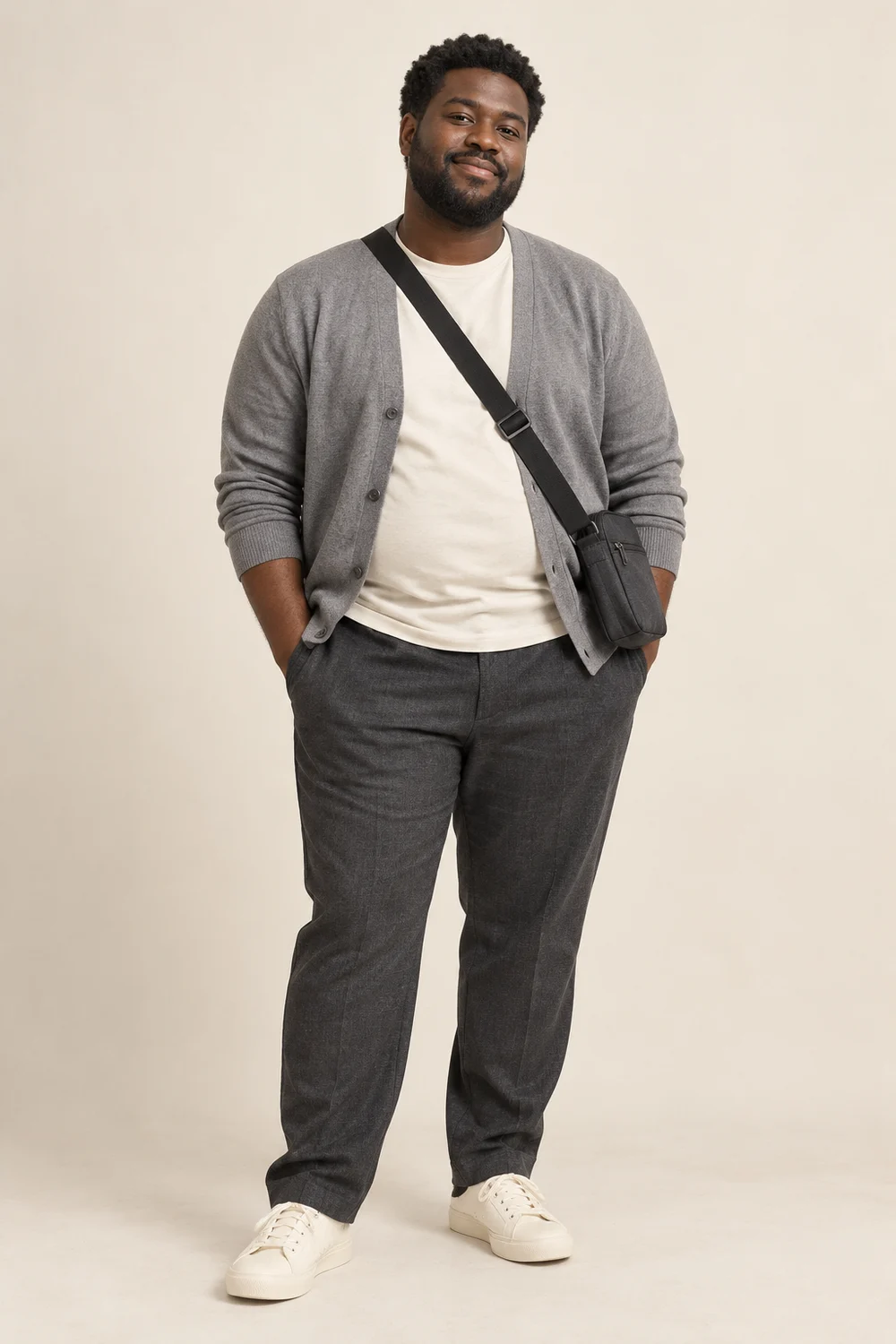 Full-length short plus-size adult man in charcoal trousers, ivory tee, grey cardigan, cream trainers and charcoal crossbody bag.