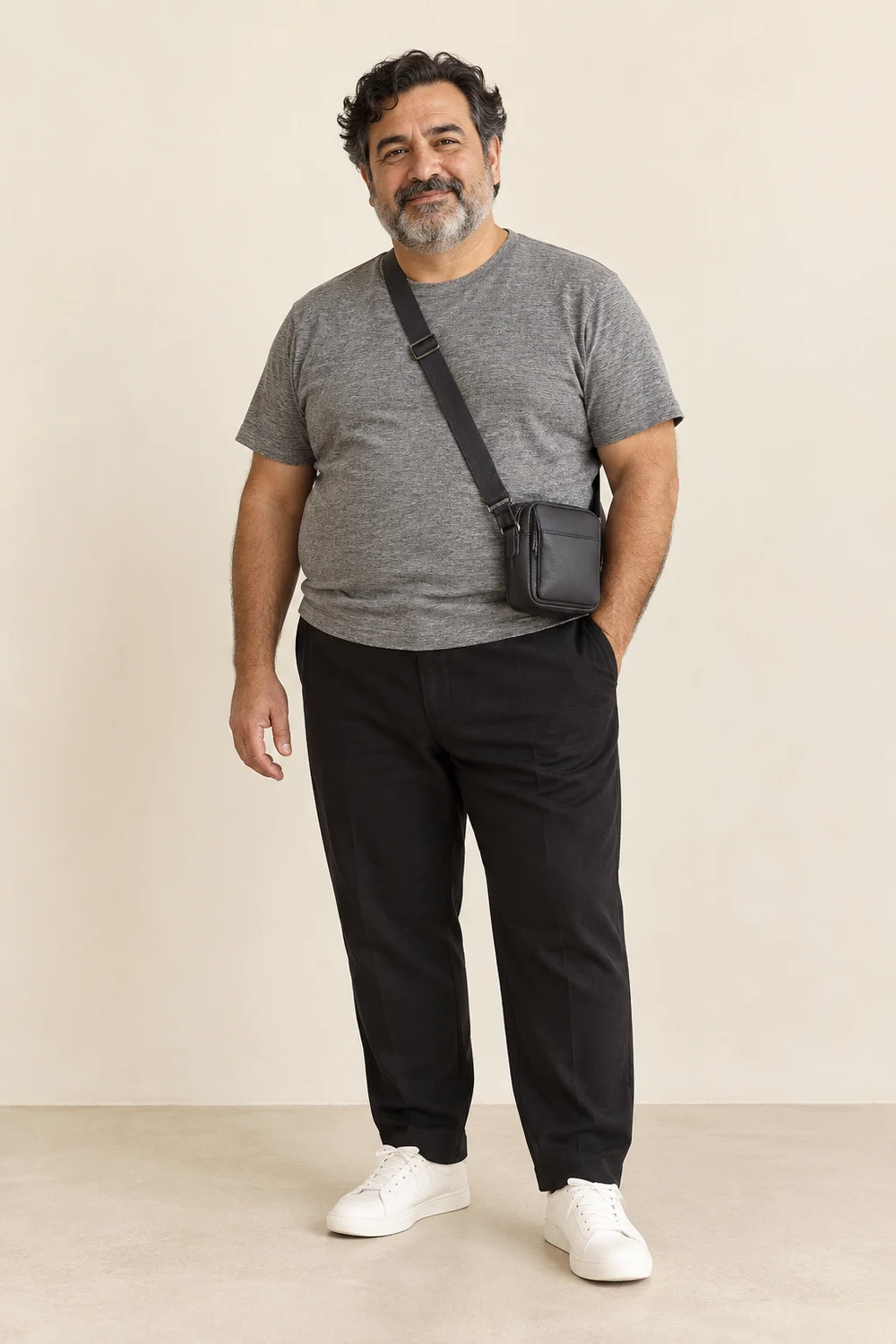 Full-length short plus-size older adult man in black trousers, grey textured tee, white trainers and charcoal crossbody bag.